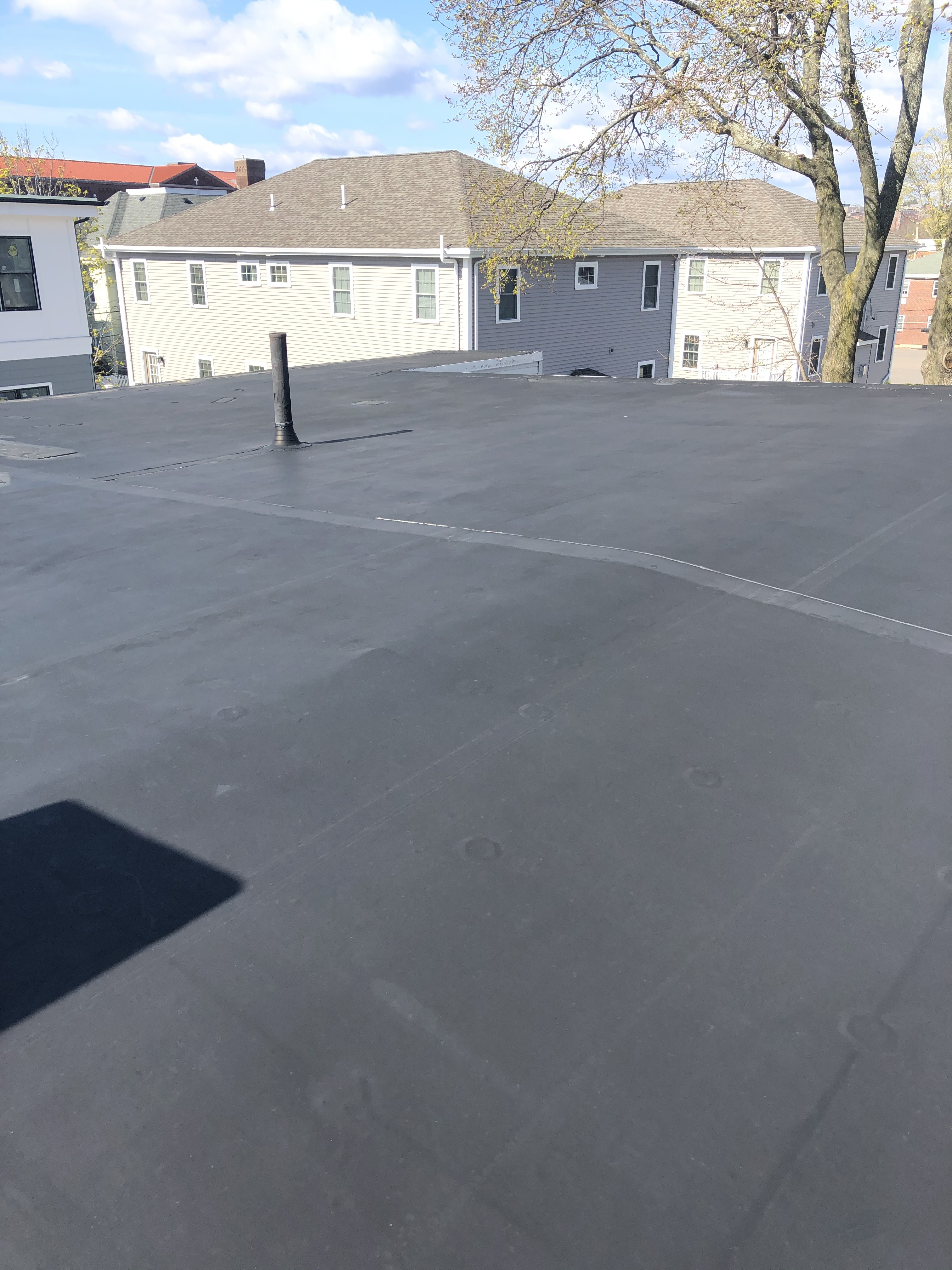 Completed black EPDM flat roof with chimney flashing installed by Storm King Roofing in Waltham, MA