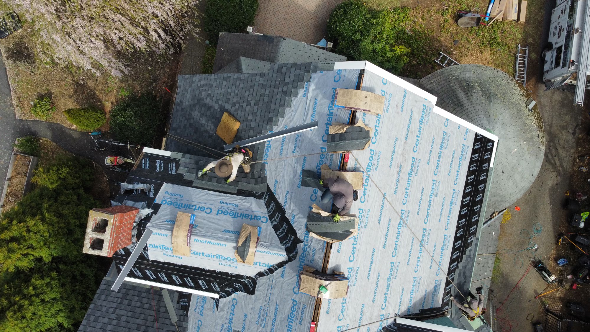 Aerial view of Storm King Roofing crew installing architectural shingles over CertainTeed underlayment on a large multi-gable home in Duxbury, MA