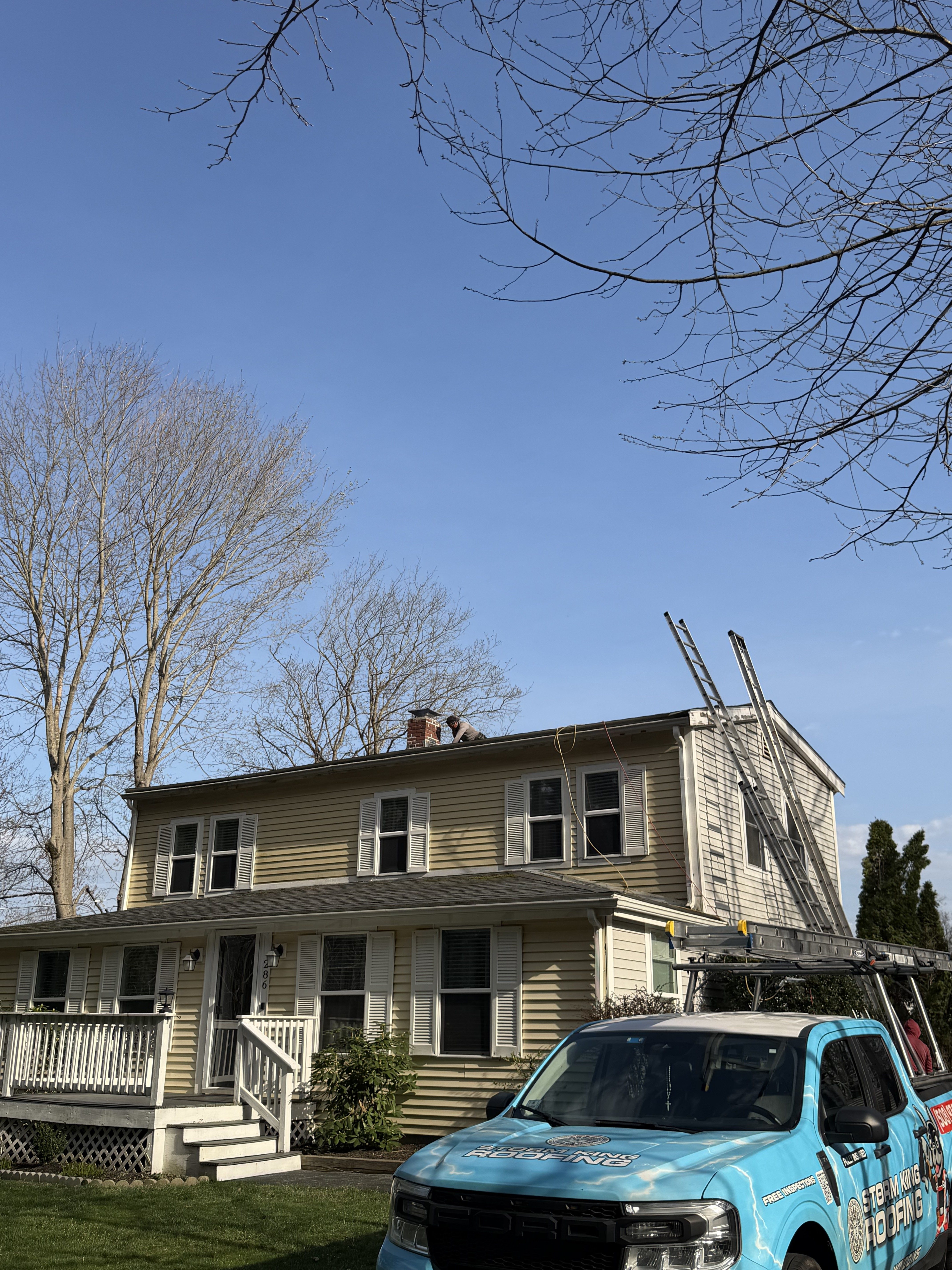 Storm King Roofing truck and crew working on a multi-family siding and chimney project in Abington, MA