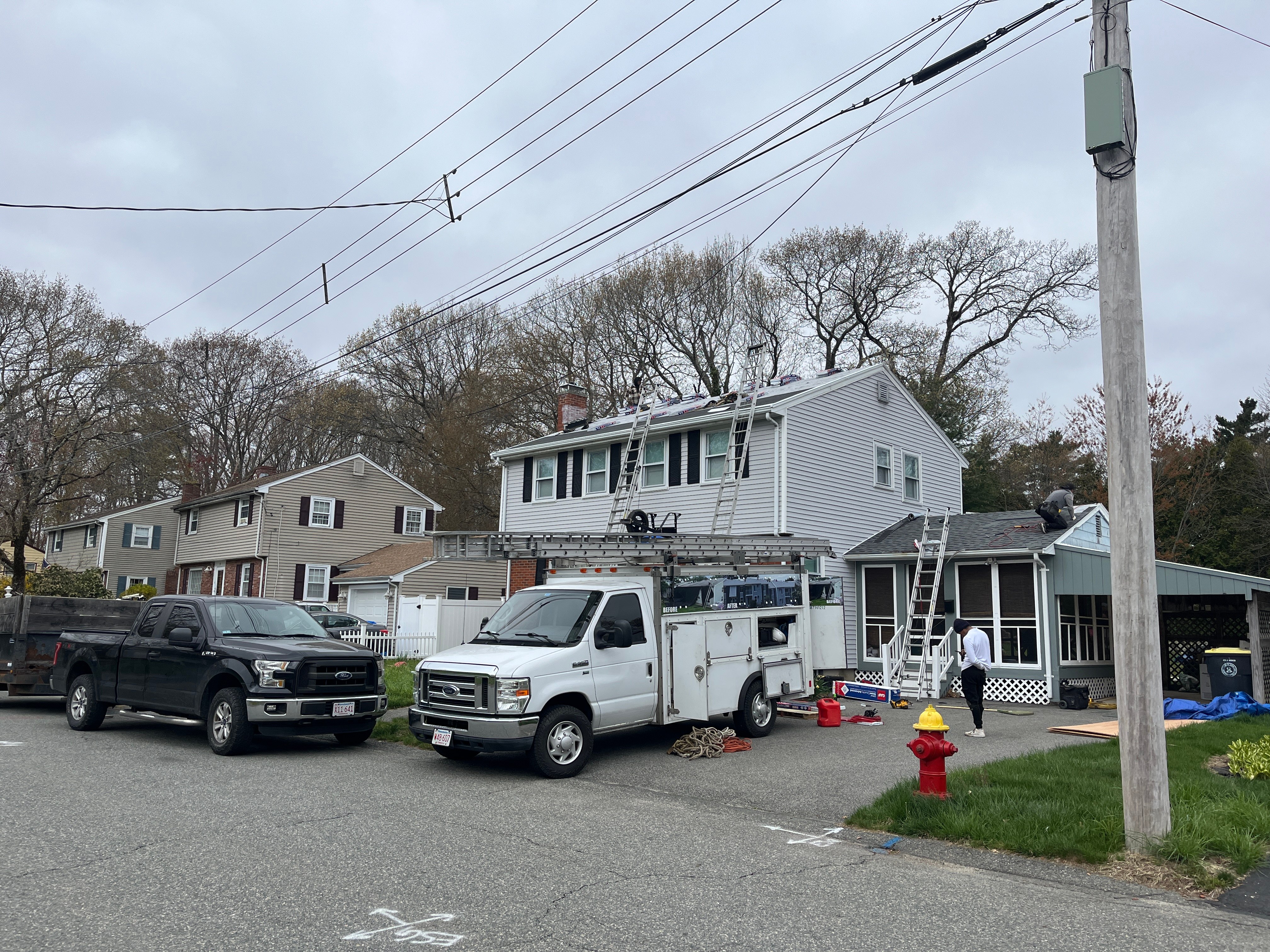 Storm King Roofing trucks at a roofing and siding job on a colonial home in Avon, MA